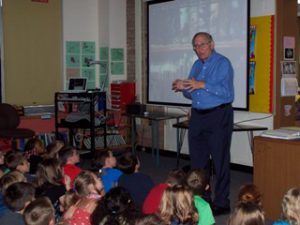 author presenting to students sitting on carpet.