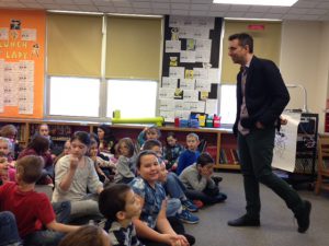 author talking to happy student sitting on a carpet floor.