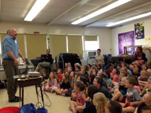 author talking to a group of students who are sitting on the floor.