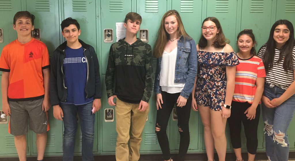 Seven students pose by lockers for a smile