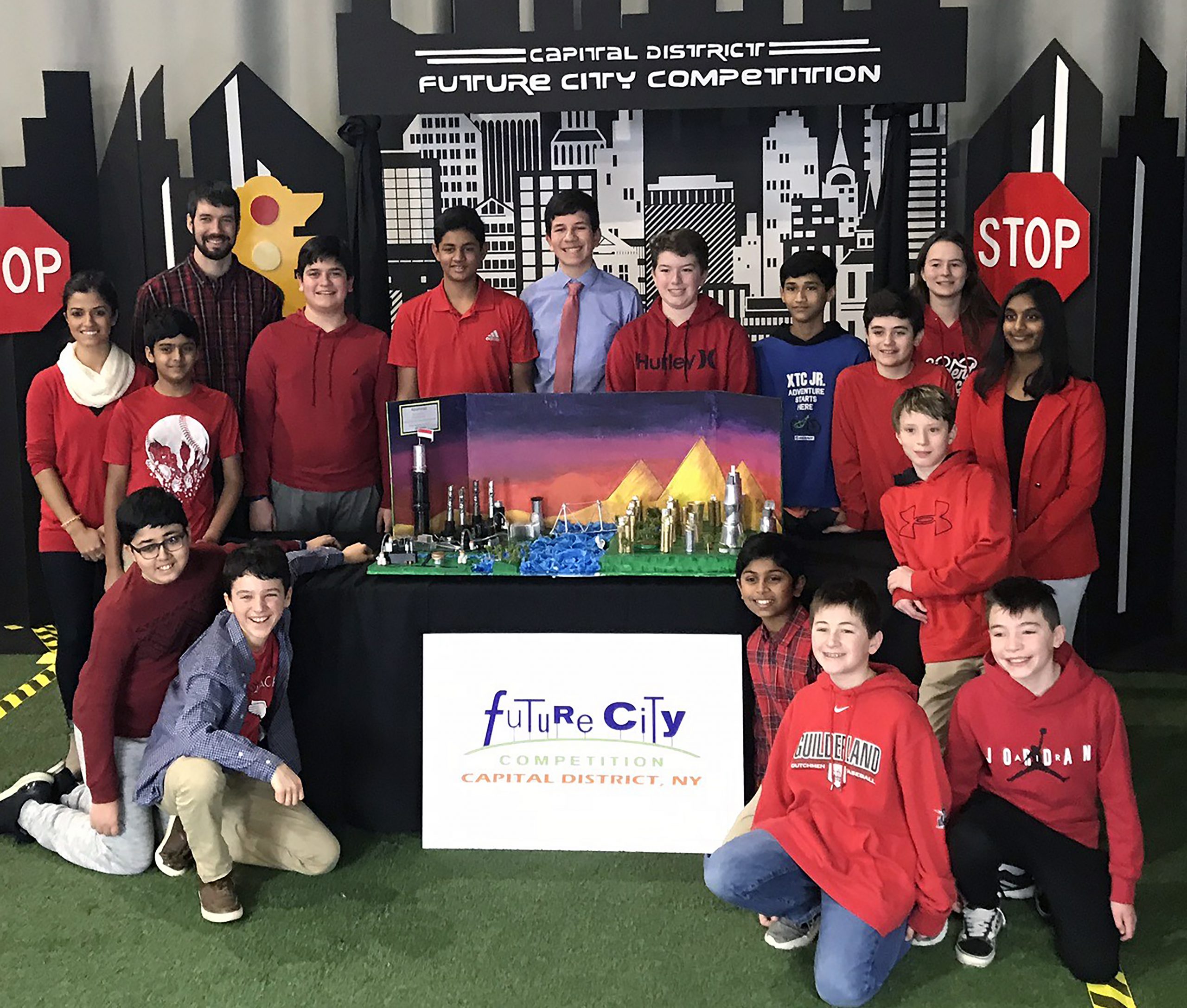 The FMS Future Cities team smiles for a photo in front of their model city