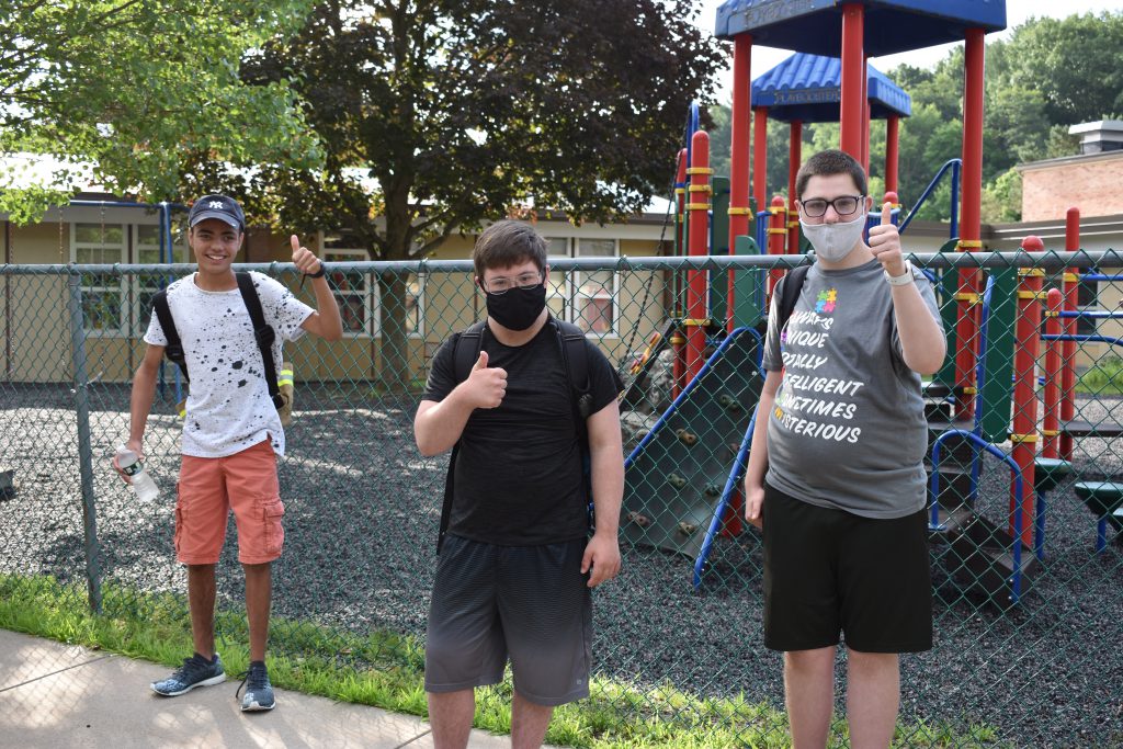 three students giving the thumbs up