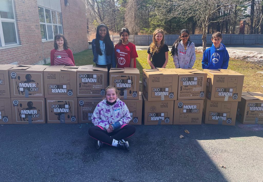 Alyssa Jantzen and her classmates smiling with the the many boxes of donated items for Ukraine.