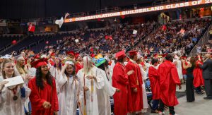 GHS students wearing red and white robes celebrate and throw their caps in the air