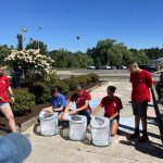 Student volunteers wearing red t-shirts open boxes to release butterflies.