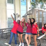 four students wearing red t-shirts standing in the butterfly garden
