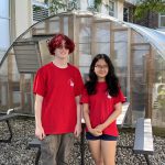 two student volunteers wearing red t-shirts standing in the butterfly garden