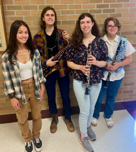 Four GHS students smiling, three are holding musical instruments.