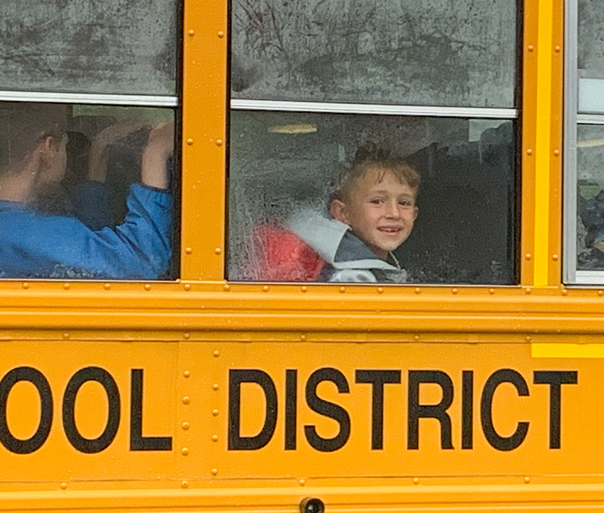 Altamont Elementary student sitting on a bus, smiling out the window.