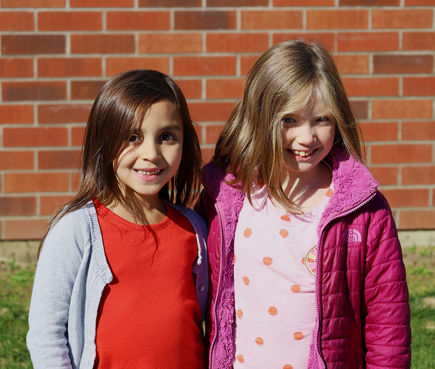 Two Pine Bush Elementary students standing next to each other outside during recess.