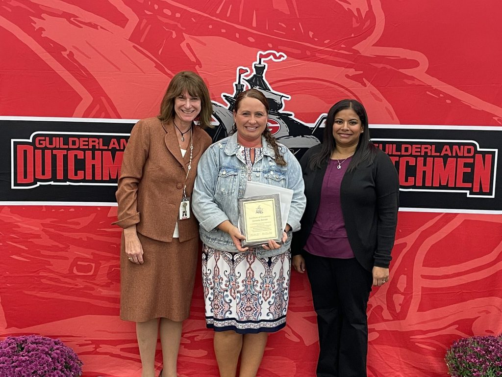 District superintendent and Board of Education president posing for a photo with an award recipient.