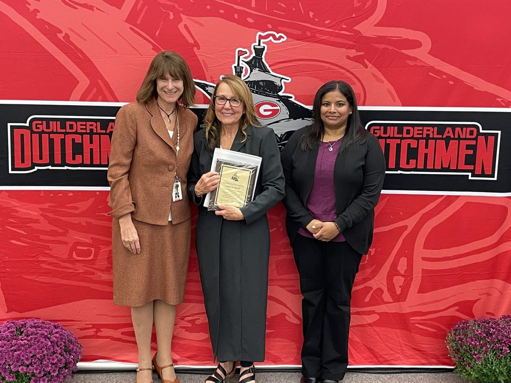 District superintendent and Board of Education president posing for a photo with an award recipient.