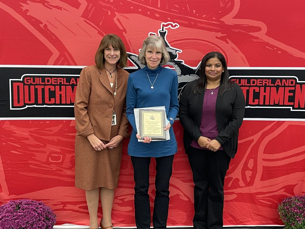 District superintendent and Board of Education president posing for a photo with an award recipient.