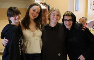 Four students smile with their arms around each other.
