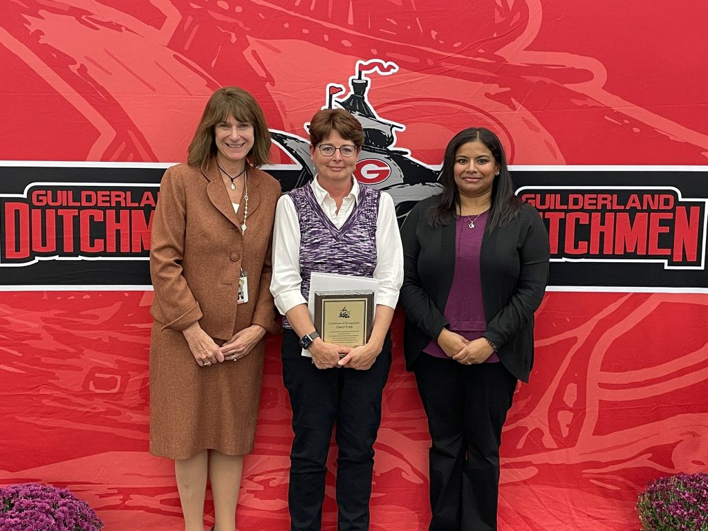 District superintendent and Board of Education president posing for a photo with an award recipient.