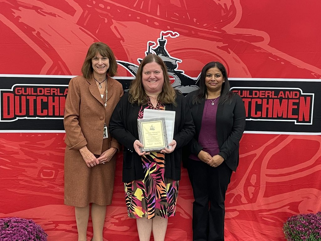 District superintendent and Board of Education president posing for a photo with an award recipient.