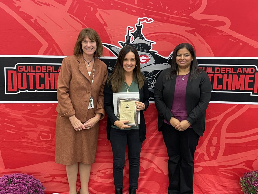 District superintendent and Board of Education president posing for a photo with an award recipient.