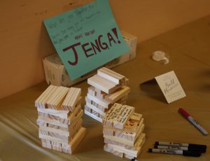 A Jenga game with a sign asking "what are you grateful for?". Students have written on the Jenga game pieces.
