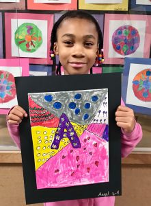 Student holds colorful artwork up for the camera.