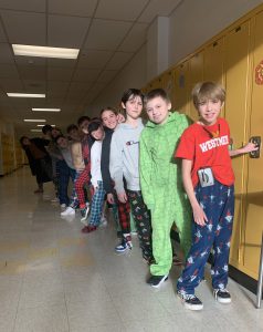 Students lined up in a school building hallway, wearing pajamas.