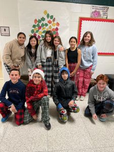 Students standing and kneeling in a classroom, wearing pajamas to school for PJ day.