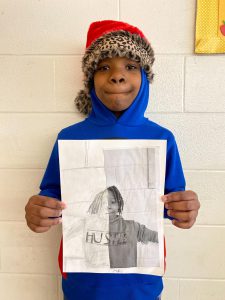 Student holds artwork for the camera.