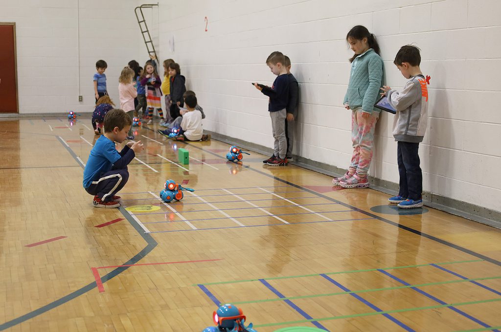 Students coding on iPads and playing with robots.