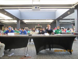 Students are seated at rows of large desks, the FMS students are in the foreground. The students are using pencils to work on math problems.