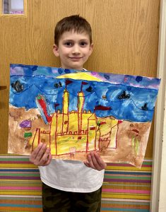 Student holds colorful artwork