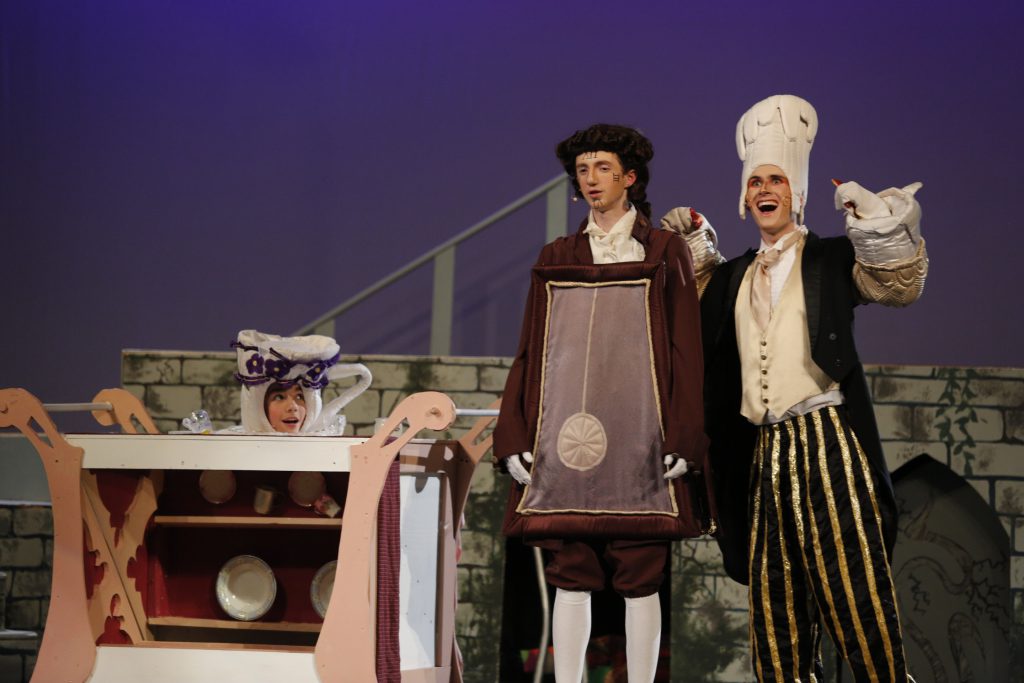 Students in costume rehearse Beauty and the Beast. One student is dressed as a clock and one as a candle.