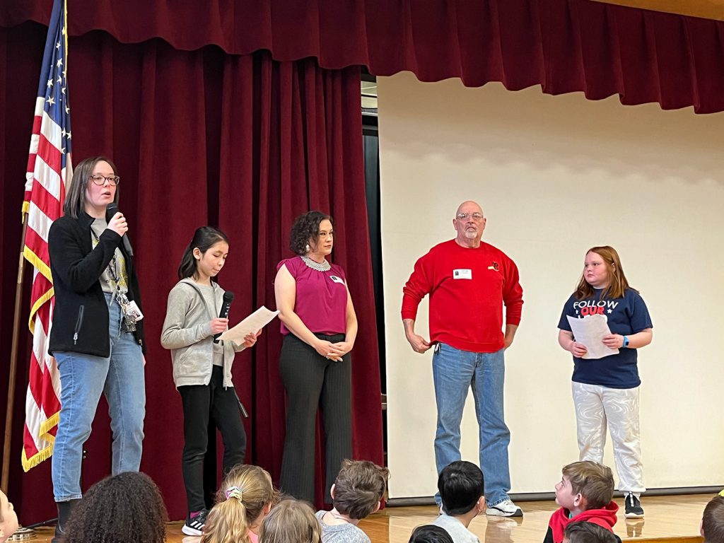 Two students and three administrators standing on stage.