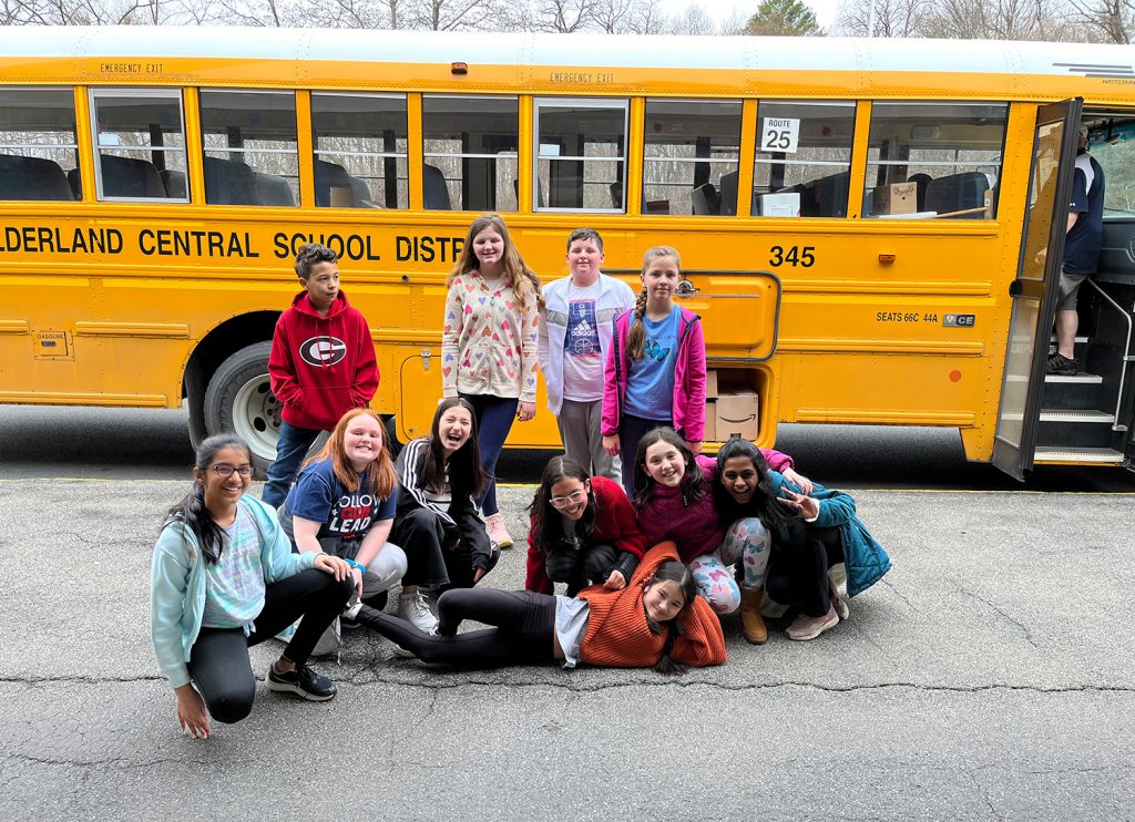 Students standing in front of a school bus.