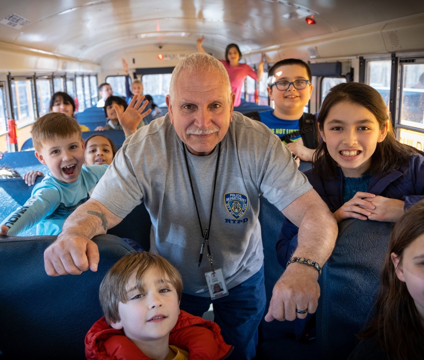 Students pose with bus driver for a photo in the the aisle of the bus.