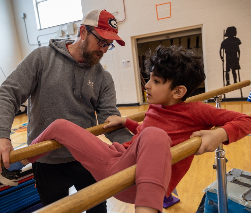 Physical Education teacher helps a student balance during a gymnastics lesson