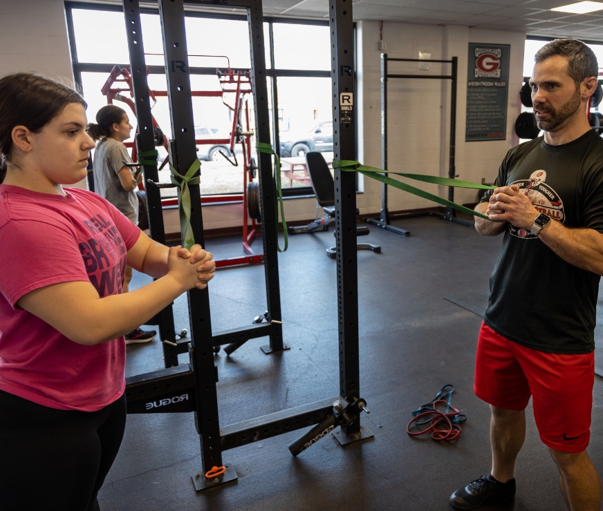 A teacher shows a student a stretching technique.