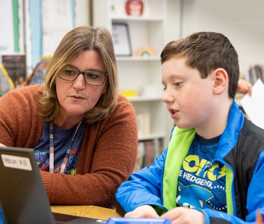 A teaching assistant helps a student during a one on one lesson.