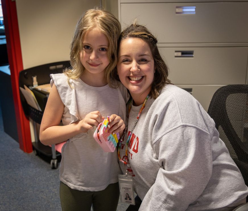 Front office worker poses for a picture with student that stopped by to say hello.