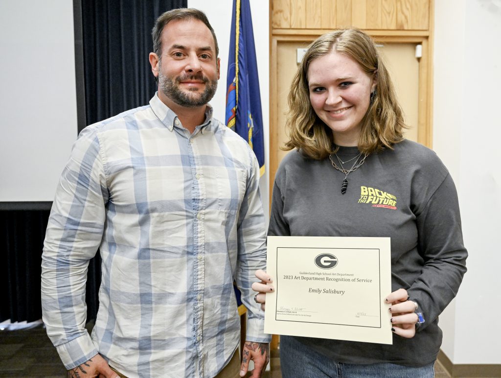 Student holds certificate next to adult.