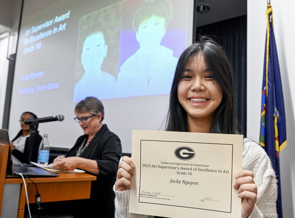 Students is smiling, holding up certificate.