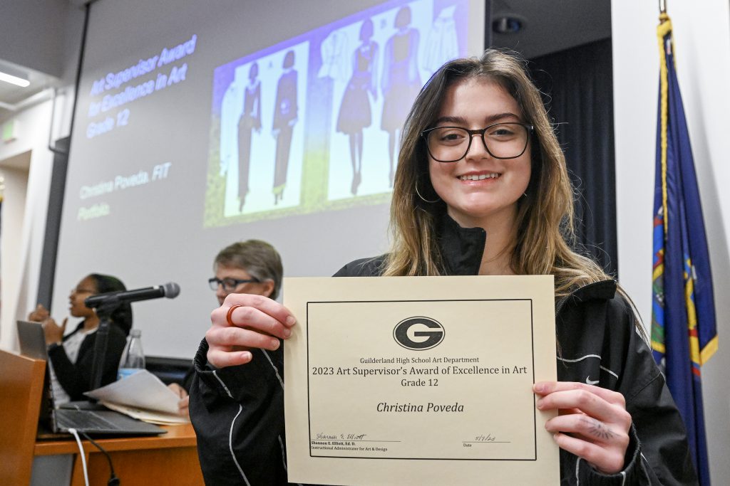 Student is smiling, displaying certificate.