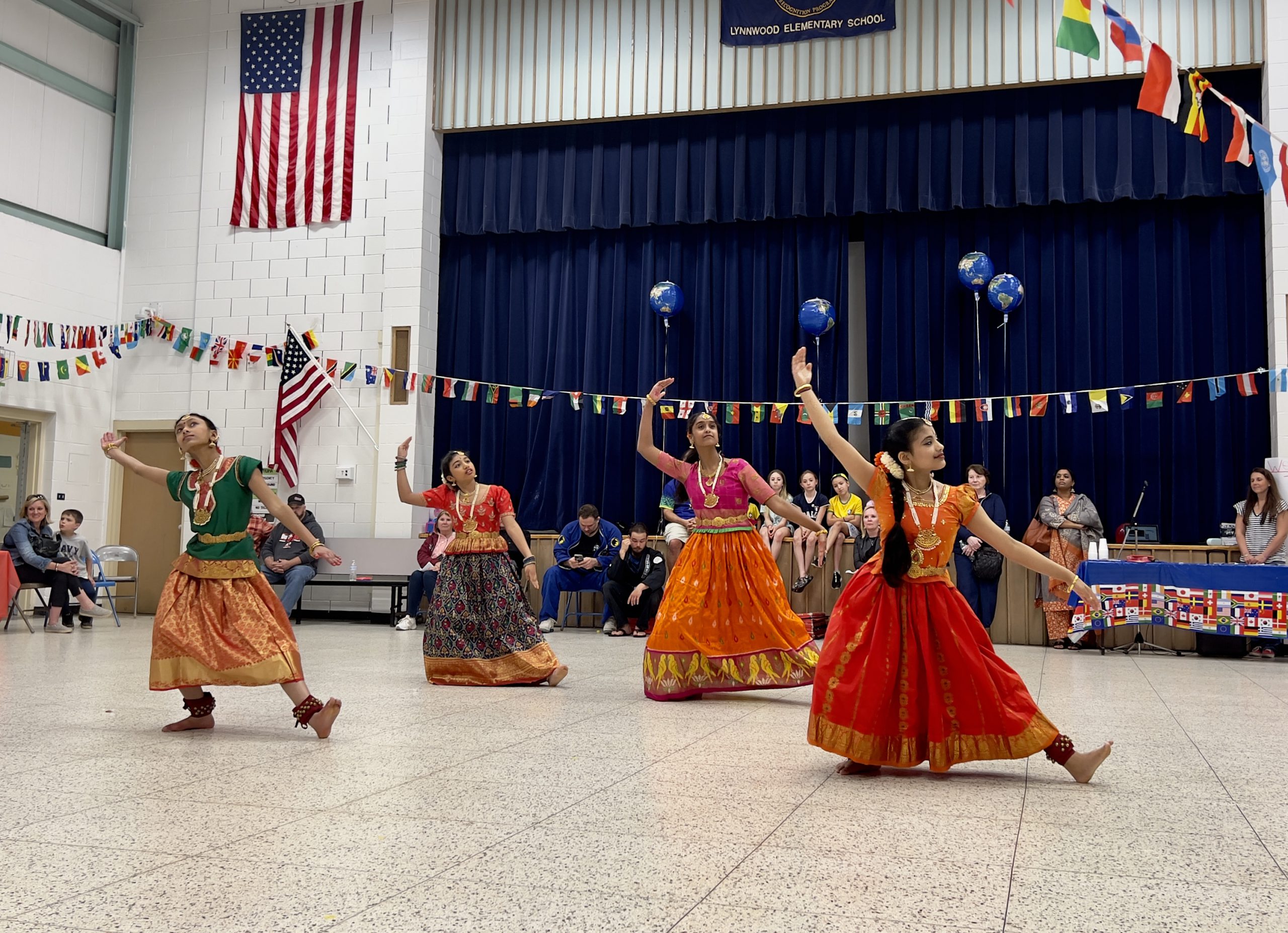 Four LES students wearing traditional clothes from their culture dance in the LES gym at the International Night event.