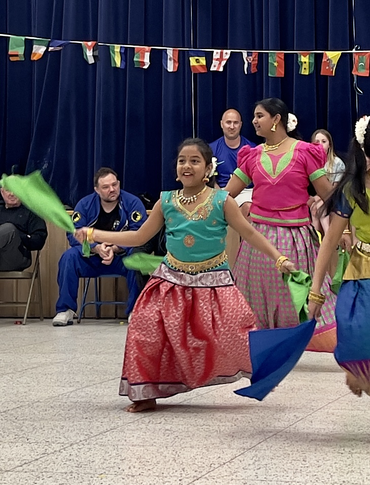 LES students wearing brightly colored traditional clothes from their culture dance in the LES gym at the International Night event.