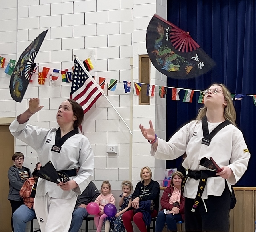 Two people wearing white traditional clothes perform jujitsu at the LES International Night event.
