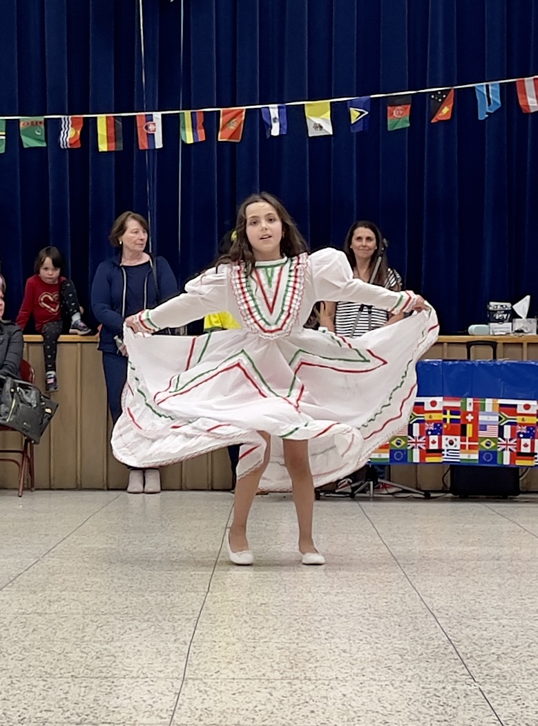A LES students wearing traditional clothes from their culture dances in the LES gym at the International Night event.