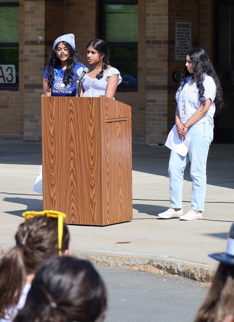 Three students speaking at the podium.