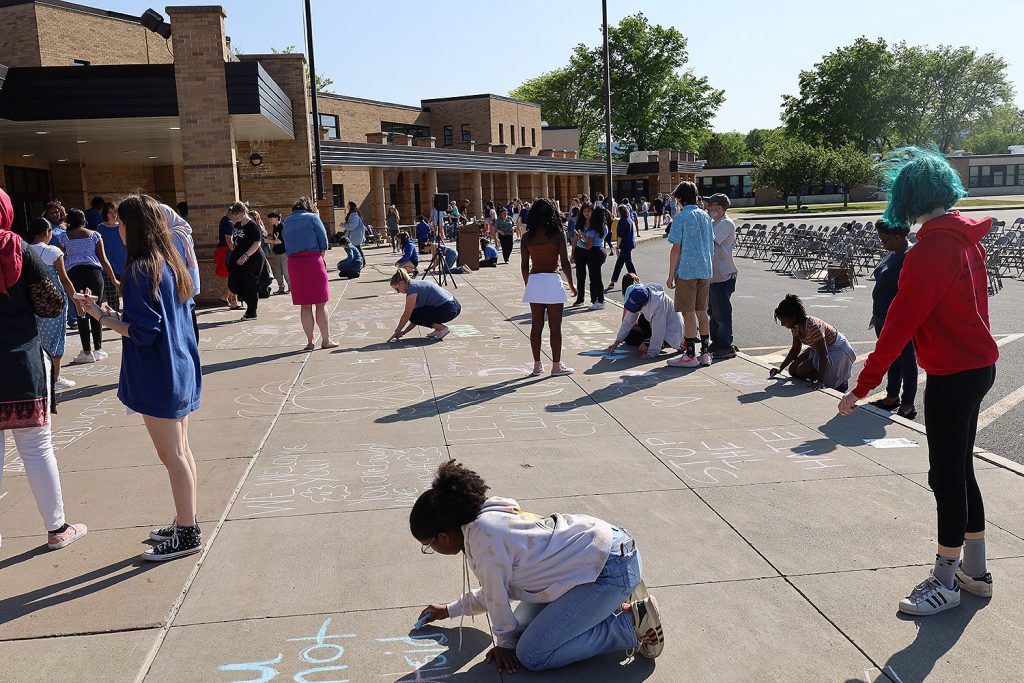 People drawing with chalk on the sidewalk.