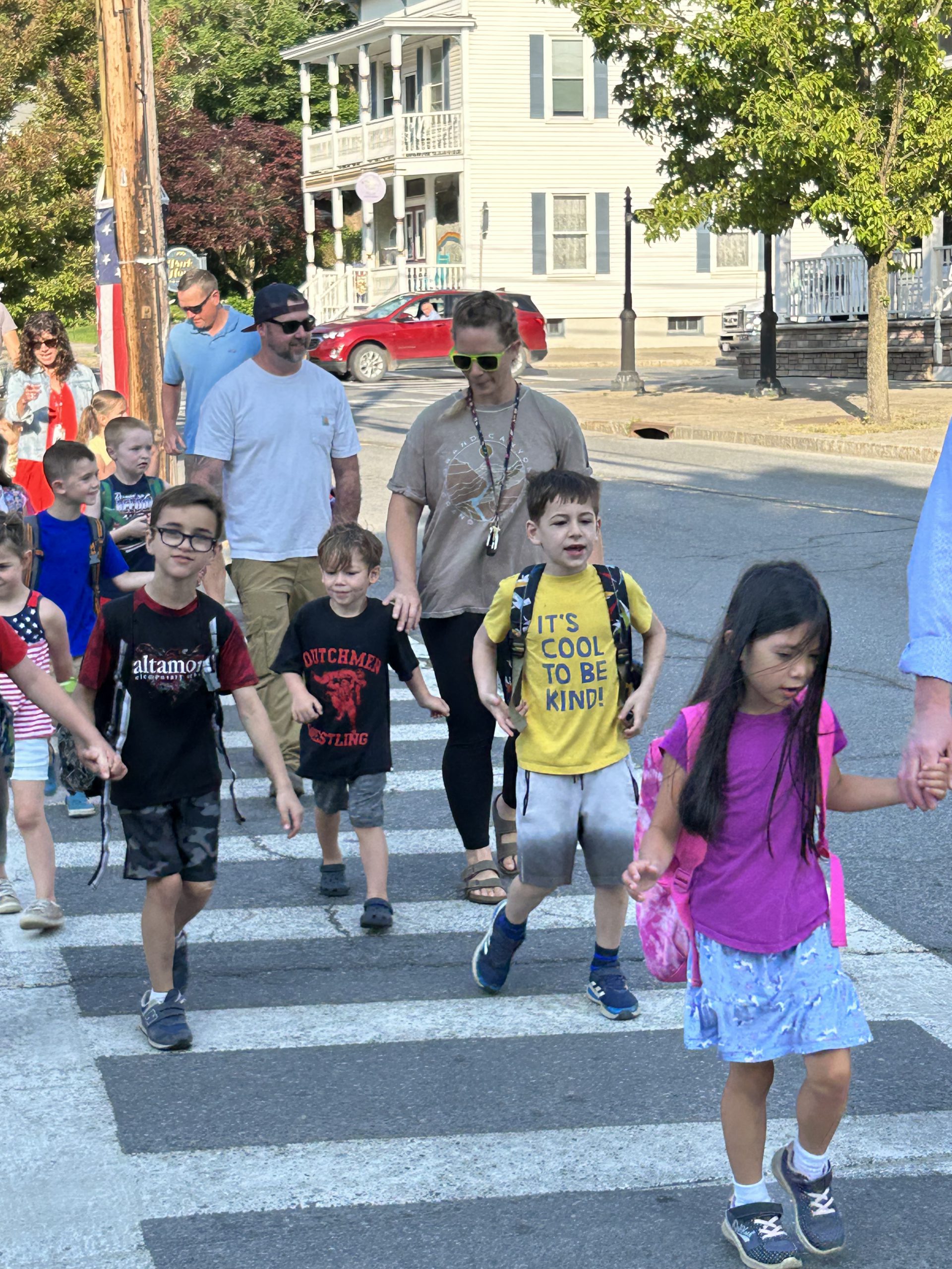 Students and parents cross a street as they walk to school.