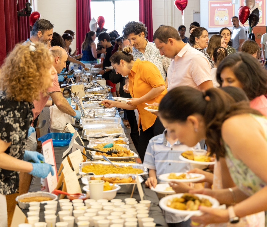 People walk through buffet line, created from ethnic foods prepared by students' families at ENL Extravaganza.