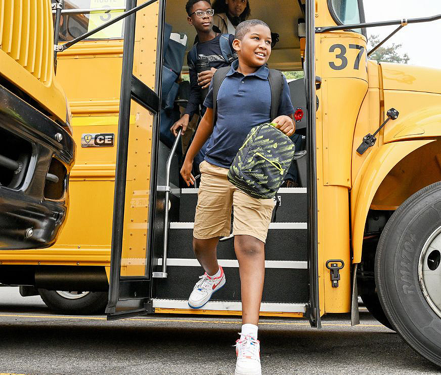 Student smiling as he steps off the school bus.