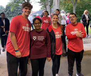 Four students stand in a line wearing red tshirts, smiling at the camera